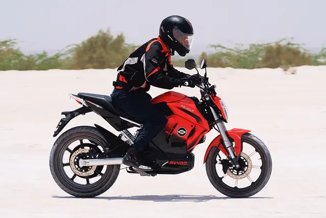 a rider wearing helmet checking revolt rv400 e bike riding modes eco red colour normal sports
