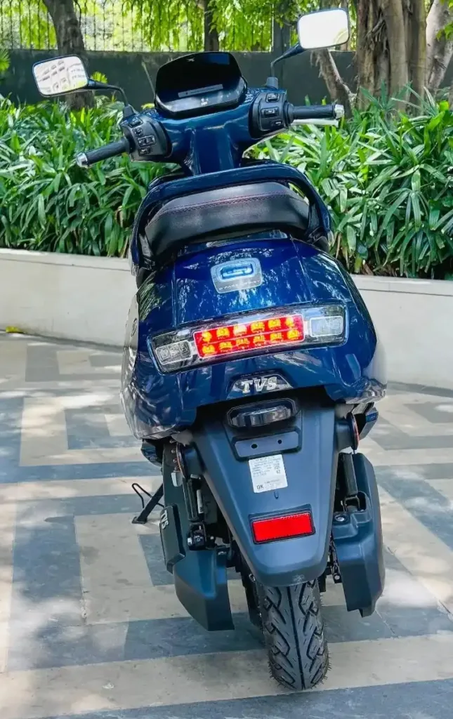 tvs iqube on road price blue colour standing in front of garden
